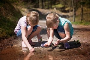 2 girls gathering stones by river